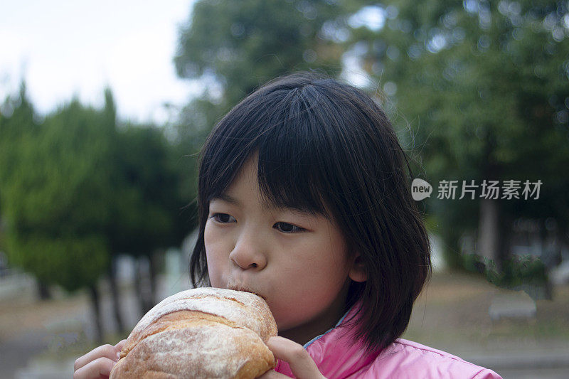 女孩在户外吃大面包