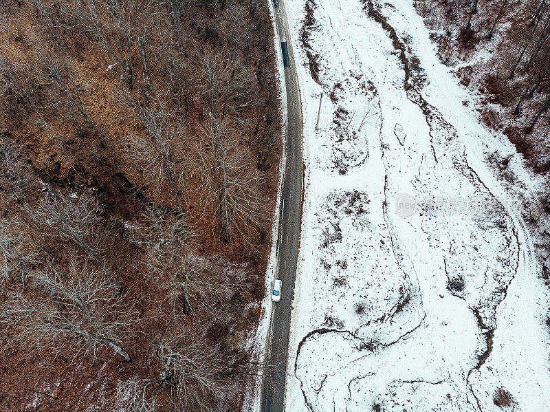 鸟瞰图的汽车行驶在乡村道路上通过雪天的冬季景观