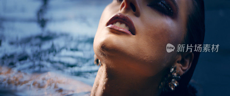 优雅的女人从水中浮现。浸湿她的长发。美容护理的比喻