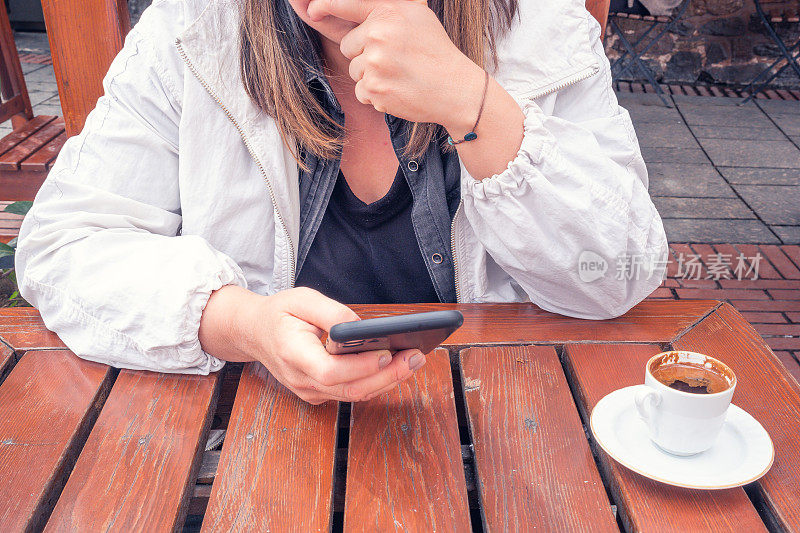 女人花时间在她的智能手机在咖啡馆
