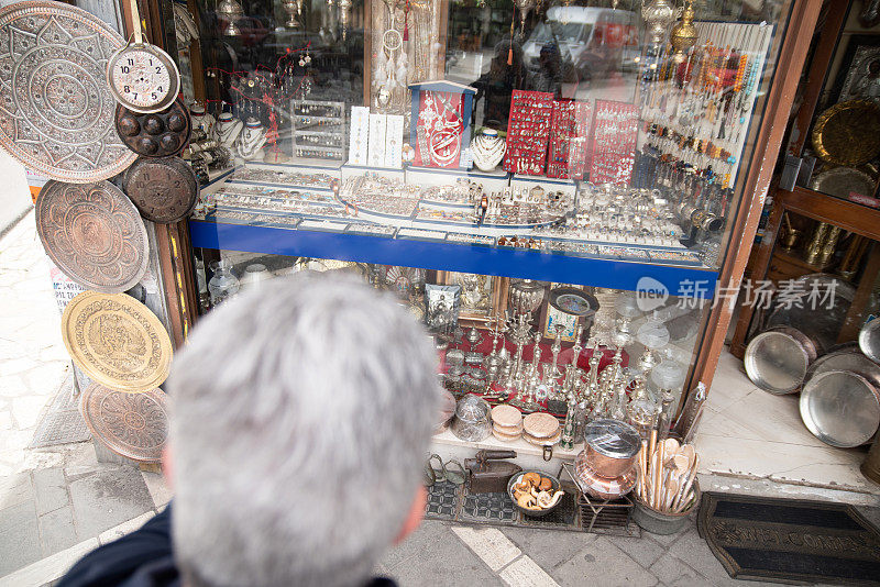 成熟的男子游客在传统的希腊礼品店寻找有价值的纪念品