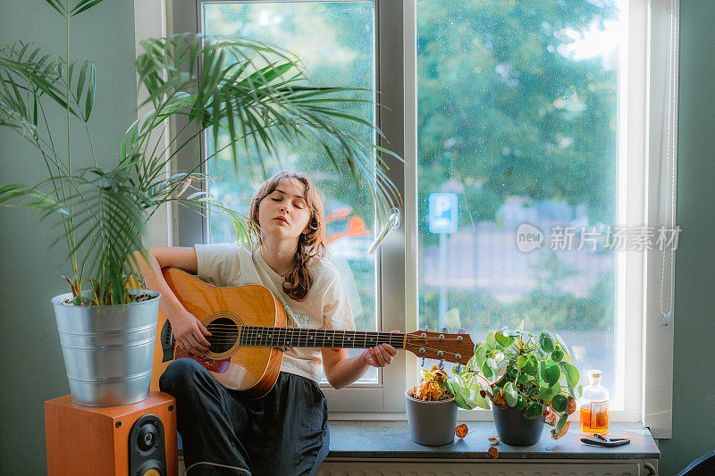 一个女人坐在窗台上弹吉他