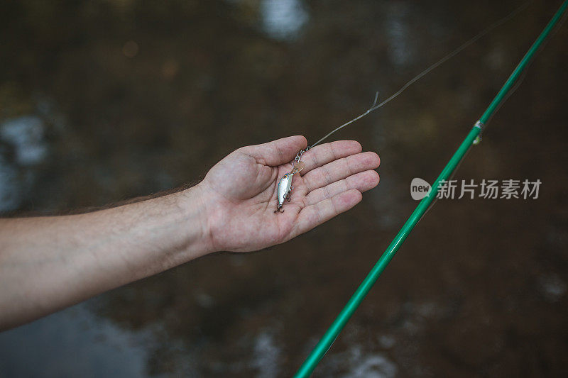 一个面目全非的渔夫正用鱼钩钩着一条钓上来的鱼