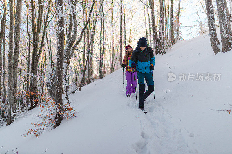 年轻的男性徒步旅行者和他的女性朋友一起从雪山小径上爬下来