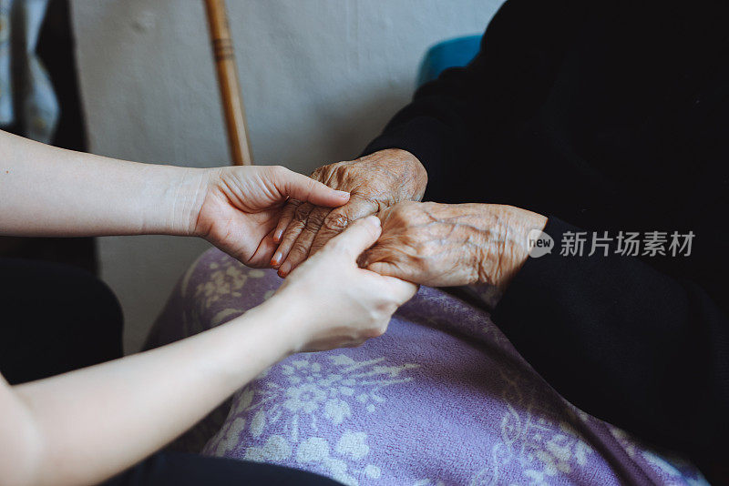 老女人的手牵着年轻女人的手，伸出援手，照顾老人的理念。