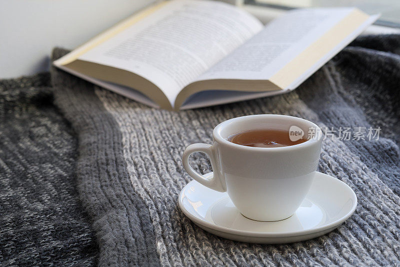 窗台上的一杯茶，暖和的羊毛衣服有助于在冬天暖和起来，花时间看一本有趣的书或教科书。