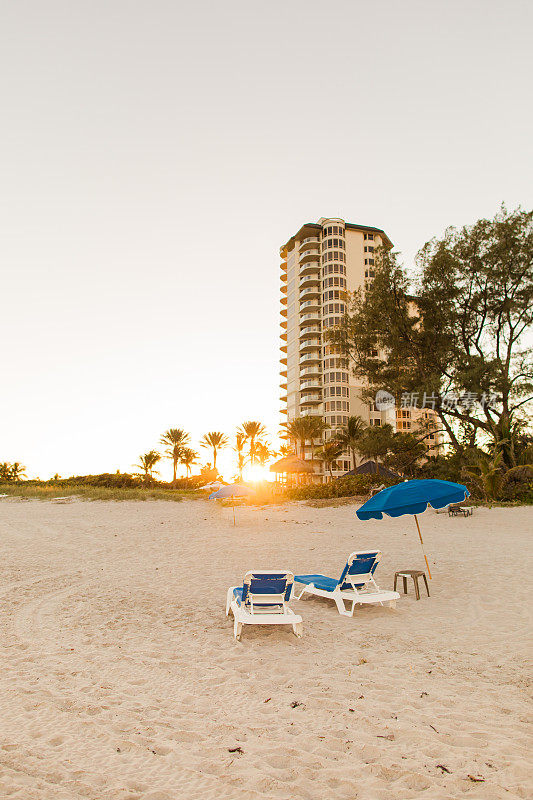2023年1月日落时分，佛罗里达州辛格岛沙滩上的蓝白沙滩躺椅