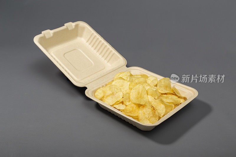 用灰色背景的硬纸板外卖包装取出薯片