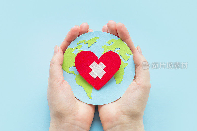 世界心脏病学家日。健康日概念。女性的手拿着一个带心形的纸质地球仪模型