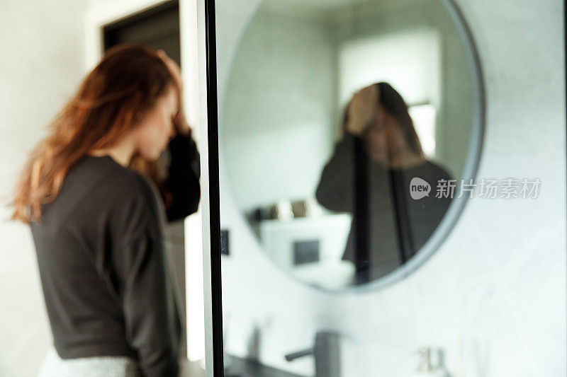 焦点深度抑郁的女人看着浴室镜子