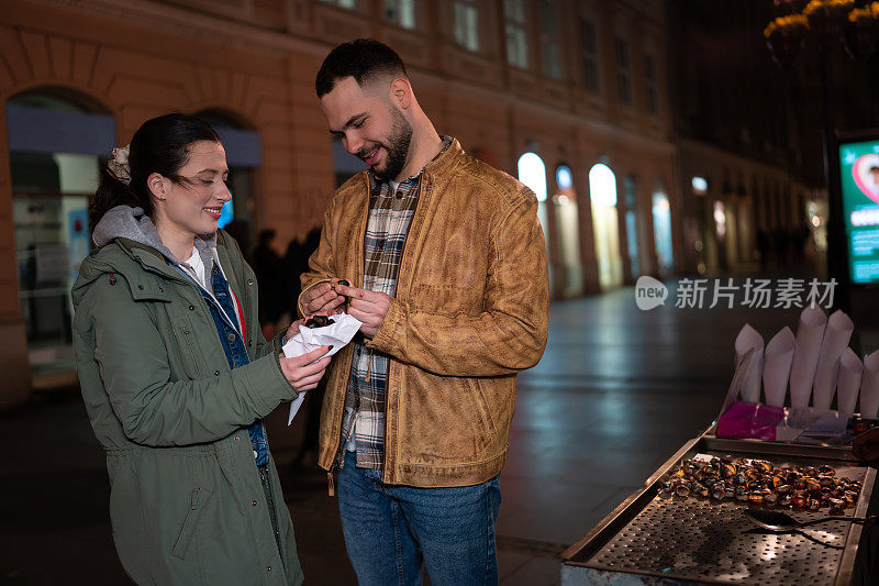 一对年轻夫妇在街上买烤栗子