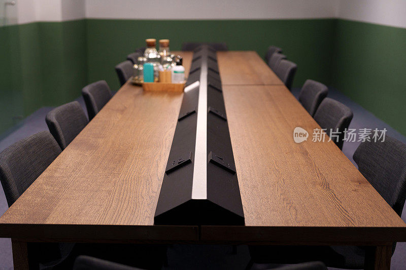 现代化会议室的内部景观，配备了方便的电源插头，舒适的办公椅和各种办公用品的原始硬木桌子。