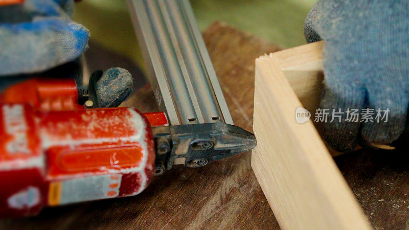 近景:亚洲资深木匠用钉枪制作家具装饰房屋。