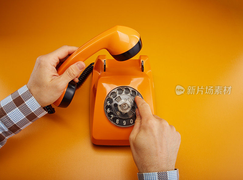 打个电话。拿着一个老式的电话听筒。一个橙色的复古电话接收机手持手持桔黄色的背景
