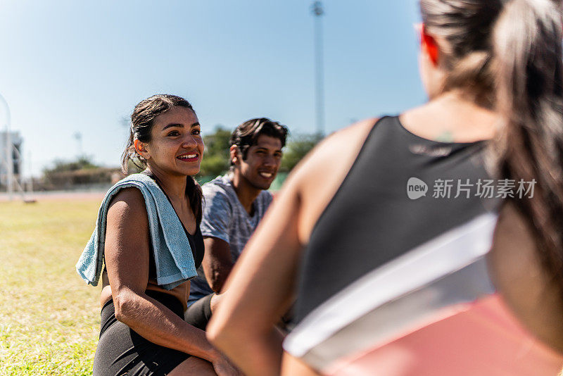 中年成年运动员和朋友坐在户外的草地上聊天