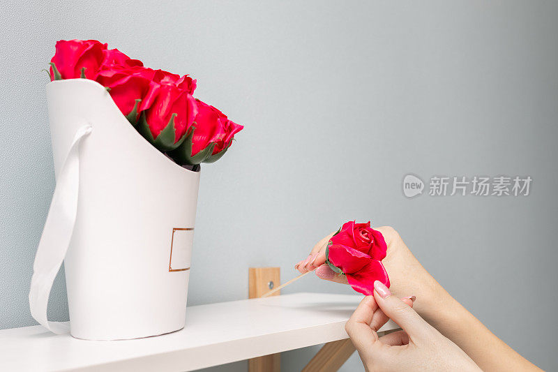 一个女人的手从玫瑰上扯下一片花瓣。
