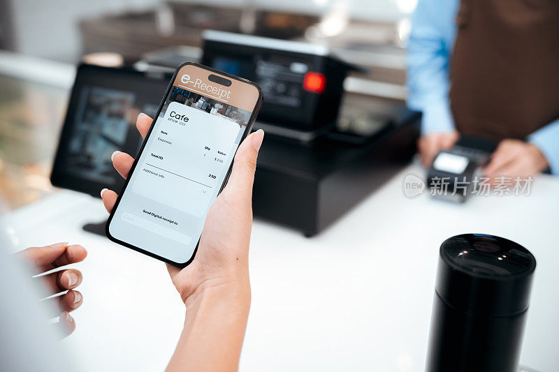 特写顾客手持智能手机在支付终端上完成电子收据