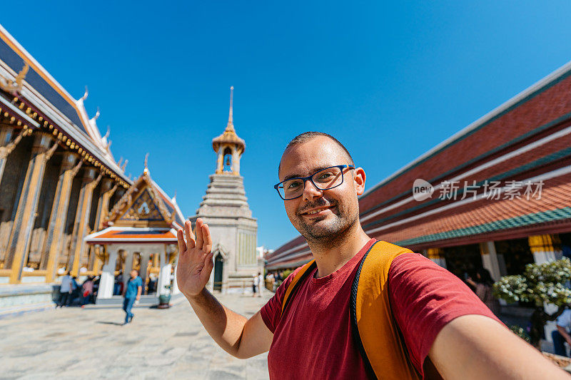 在泰国曼谷的玉佛寺，一名年轻人正在和玉佛寺进行视频通话