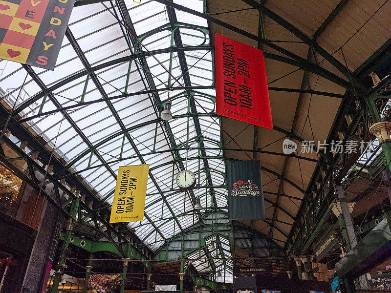 博罗市场的室内天花板，绿色钢结构下悬挂着横幅，阳光照进来