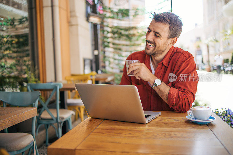 一个放松的成年人正在咖啡店里用笔记本电脑工作。