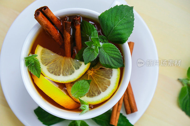 红茶和绿茶加柠檬、肉桂棒和薄荷叶。热饮。健康的玛丽莎茶，天然有机芳香饮品杯。夏，秋，冬暖饮