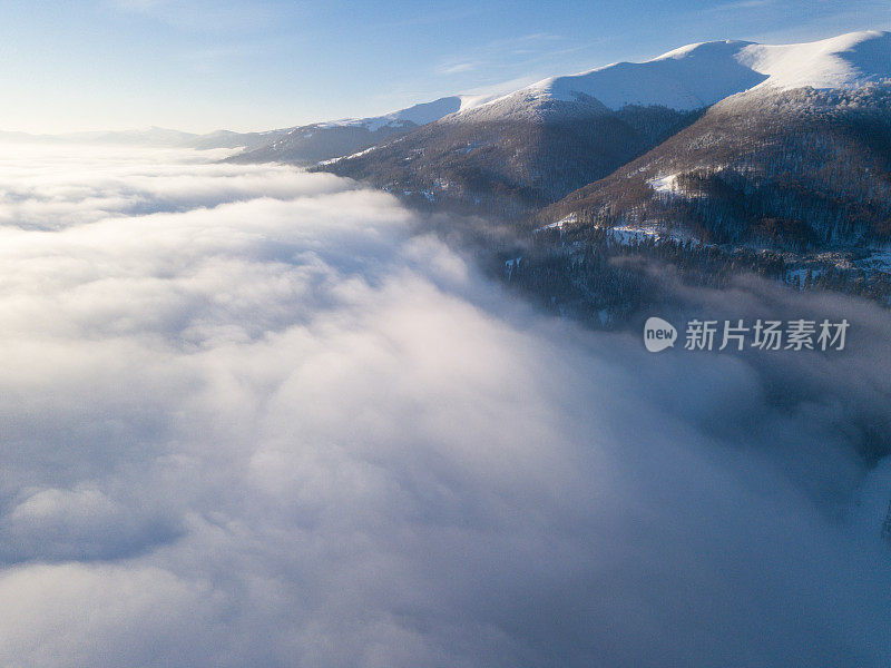 壮丽的日出在山上的空中拍摄。山与山之间的山谷被雾覆盖，被初升的太阳温暖的光线照亮。山上覆盖着天然的森林。