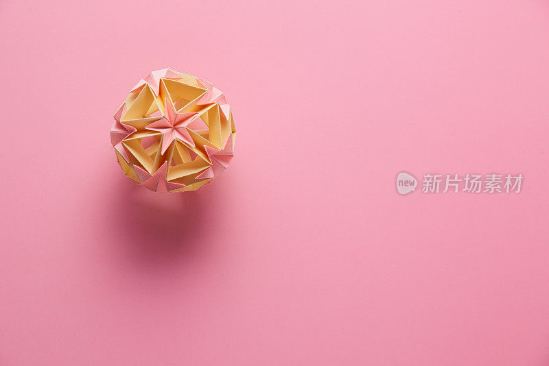 MulticolorÂ手工制作modularÂ折纸球或Kusudama孤立在粉红色的背景。视觉艺术，几何学，折纸艺术，纸工艺品。俯视图，特写，选择性聚焦，复制空间。