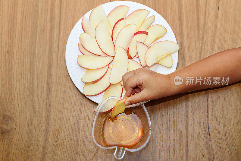 俯视图苹果片放在木桌上的白色盘子上。孩子们的手拿着苹果片