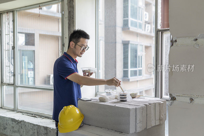 亚洲男工程师在装修工地吃外卖