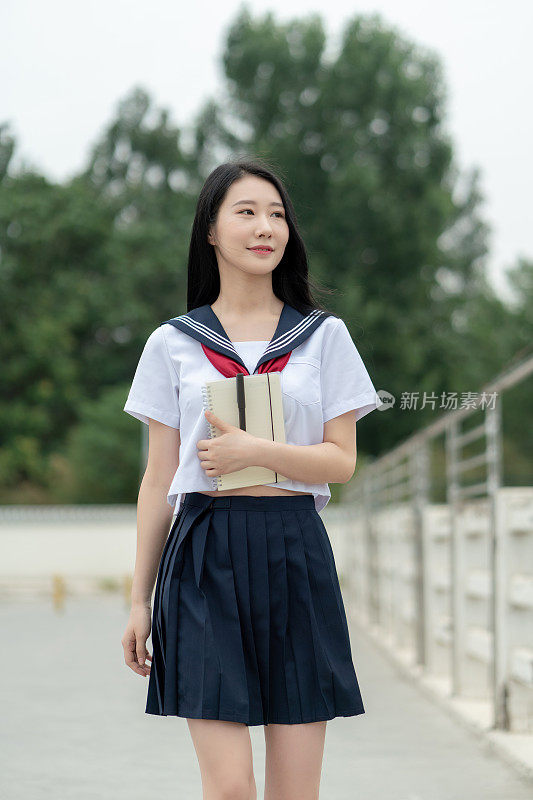 年轻的亚洲女性穿着学生服装，在大学里