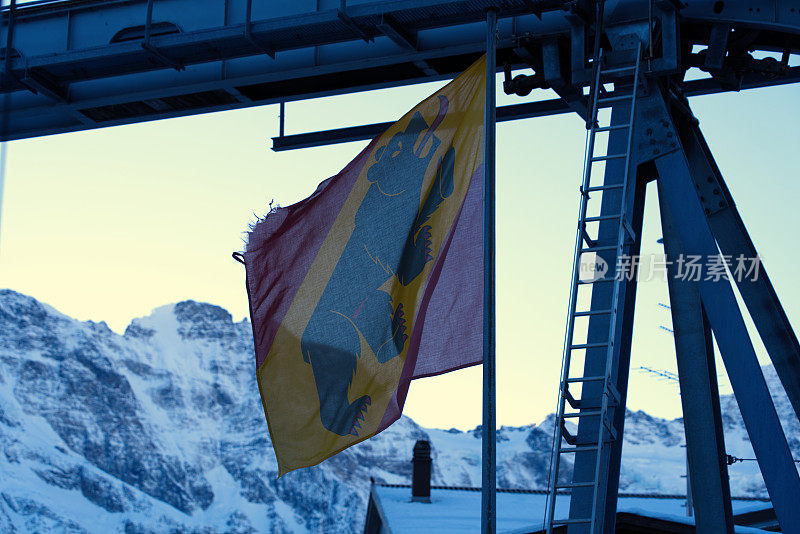 在一个阳光明媚的早晨，伯尔尼州的旗帜在山顶缆车站Mürren随风飘扬。