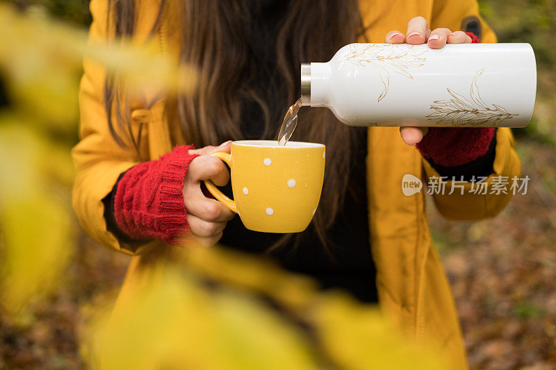 旅行家女孩在森林里从保温杯里倒茶