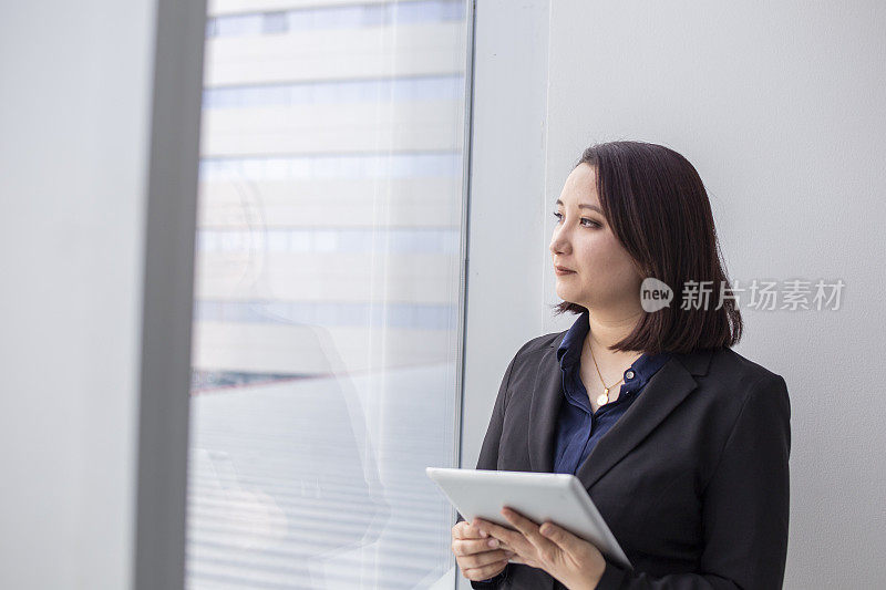 一个日本女人从办公室的窗户往外看