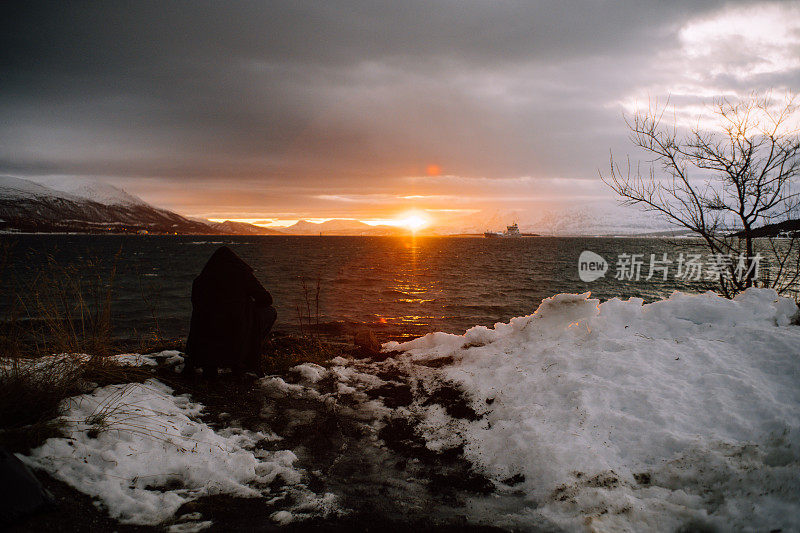 北方之旅。宁静的山景与神奇的粉红色光。湖岸上女人的剪影