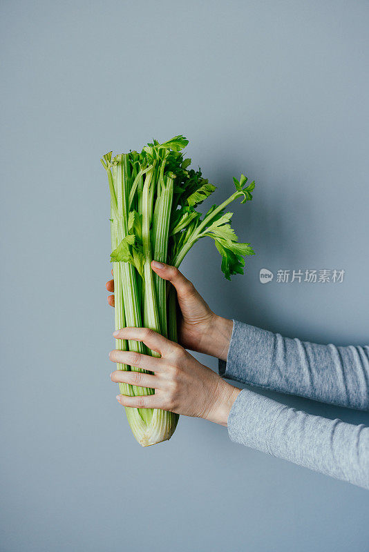 女人手握新鲜芹菜的特写照片