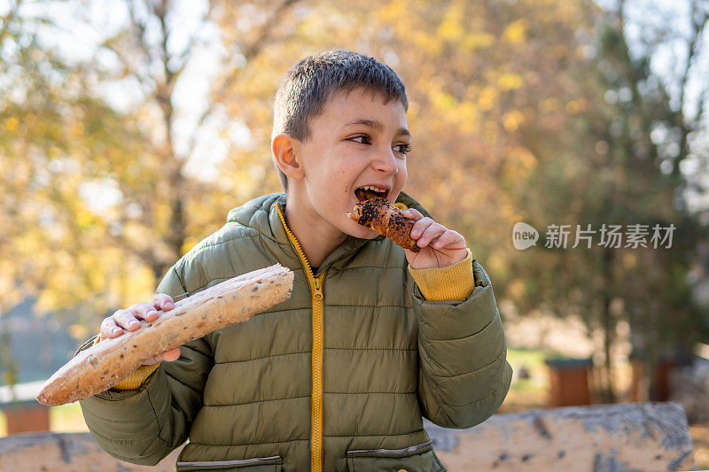 男孩在公园里吃着自制的面包