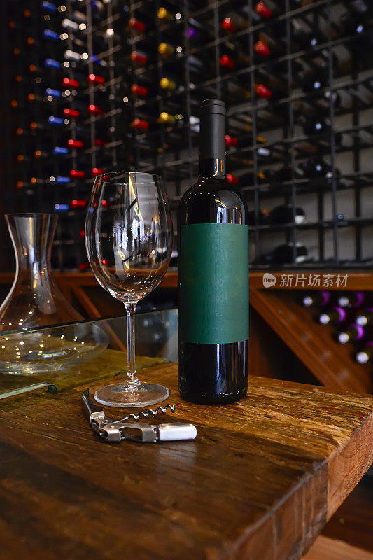 在一个迷人的餐厅地窖里，质朴的木桌上摆放着红酒酒瓶、葡萄酒杯和开塞钻。
