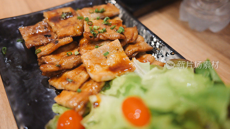 泰国一家日式餐厅的木桌上，烤猪肉米饭配上酱油装饰