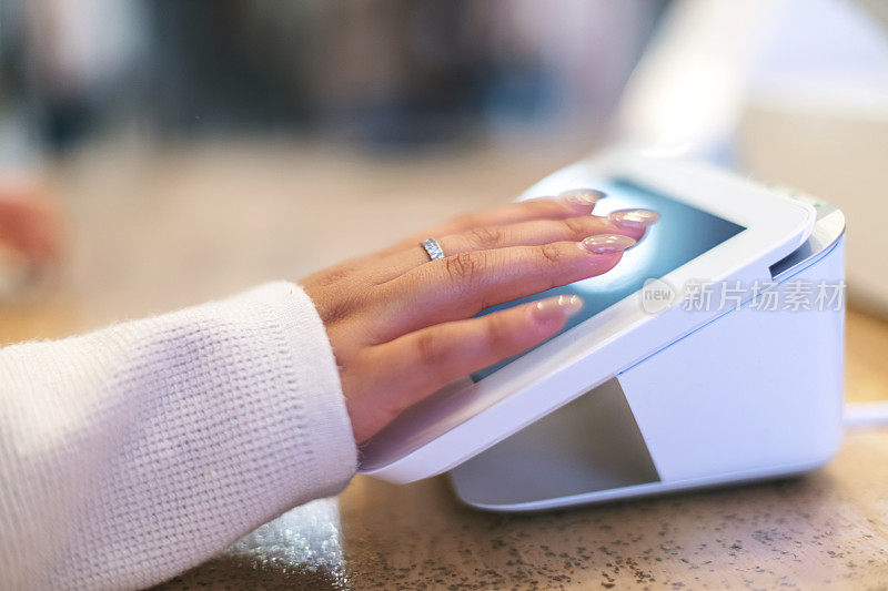 一名年轻女子的手的侧面视图进入购买的数字平板电脑在登记在零售商店小企业照片系列