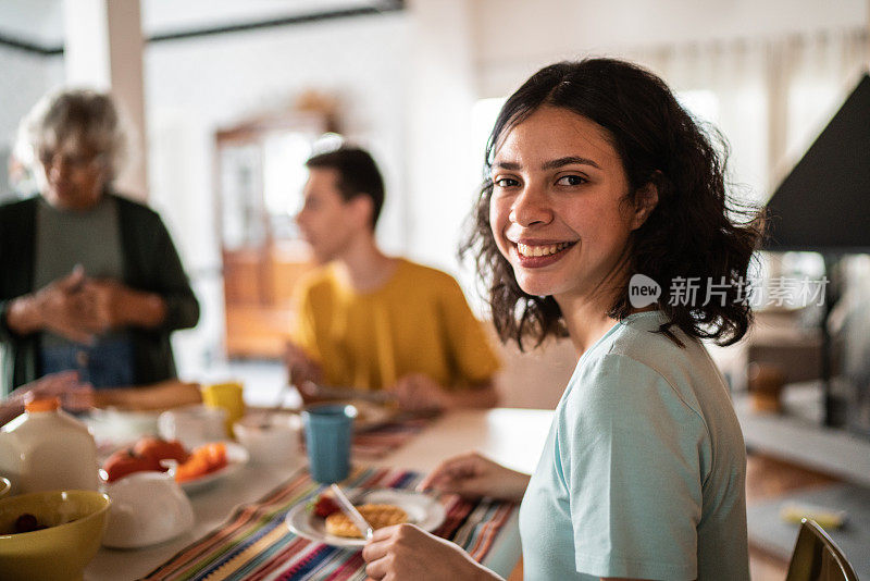 一个十几岁的女孩和家人在家里吃早餐的肖像