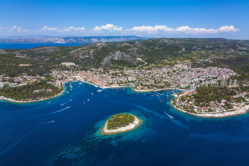 在一个阳光明媚的日子里，无人机从空中俯瞰亚得里亚海上的赫瓦尔镇，前面是一座小岛
