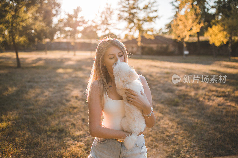 美丽的女人亲吻她的迷你马耳他犬