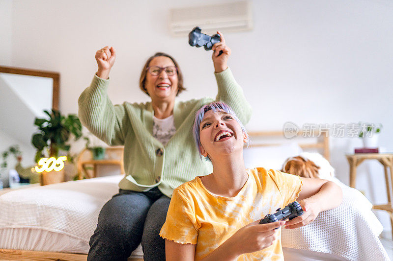 彩色头发的小女孩和她的奶奶玩电子游戏