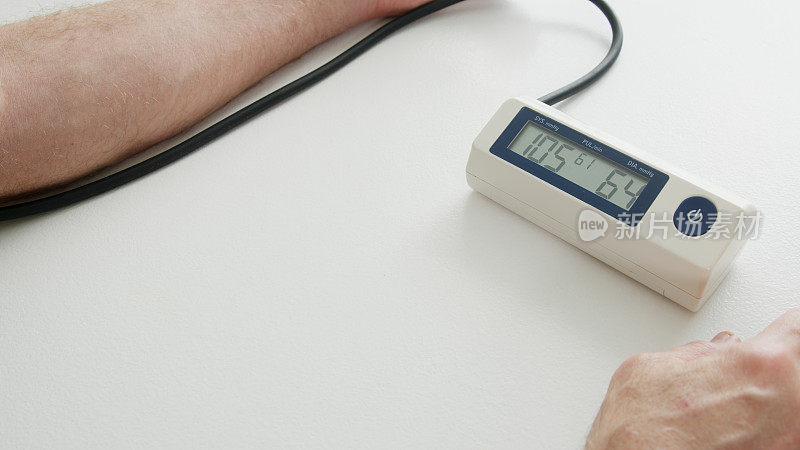 成年男子在家用桌上的血压计测量血压