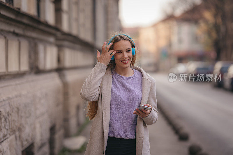 年轻自信的女人在街上听音乐的肖像