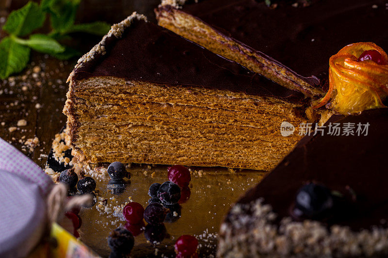 木桌上放着一块涂有醋栗、薄荷和蔓越莓的巧克力蜂蜜蛋糕。垂直方向