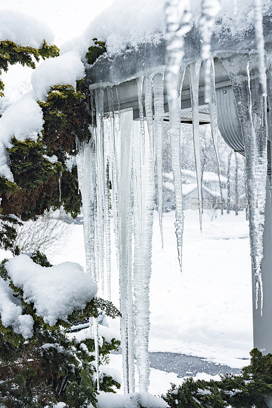 悬挂在屋顶水槽上的冰冻冬季冰柱