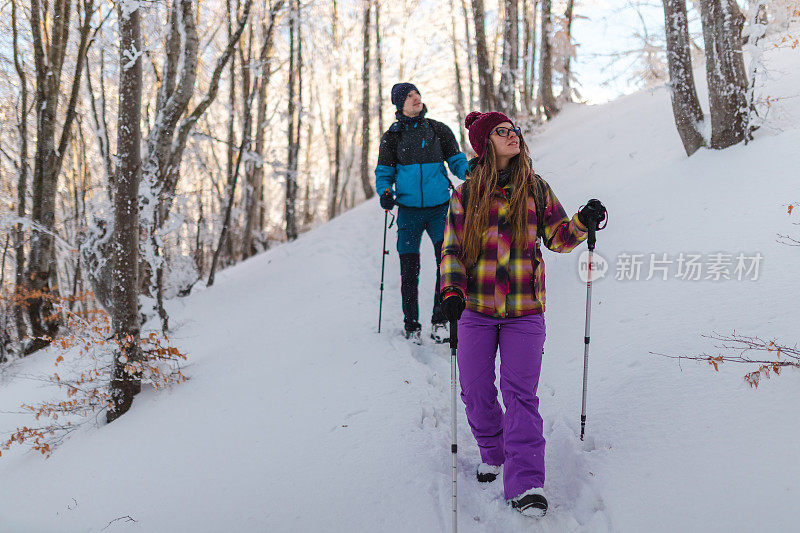 两个年轻的徒步旅行者正从雪山小径上爬下来