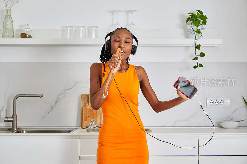 漂亮的黑人女孩戴着耳机，享受着智能手机里的音乐