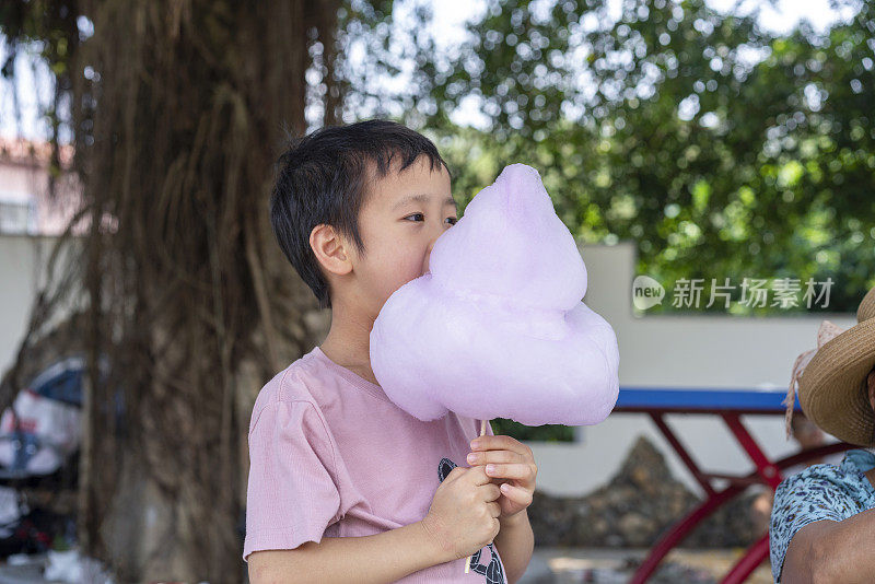 可爱的亚洲小女孩在户外吃棉花糖